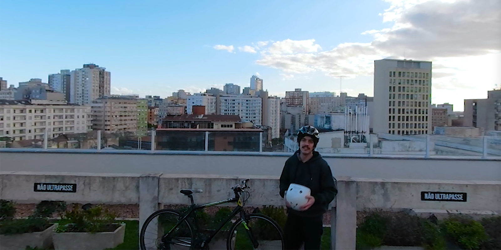 Man standing next to a bike holding his helmet