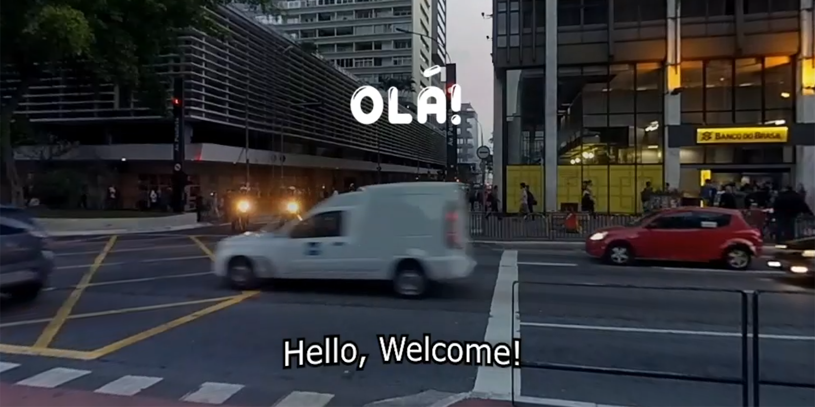 Scene of a street with Olá and Hello, Welcome captions overlaid