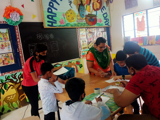 Group of students and teacher at a table surrounded by artwork.