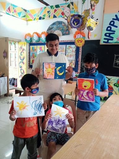 Students holding up papers with artwork.