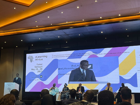 Senegalese Prime Minister Abdoulaye Ba stands at the podium at the eLearning at the opening plenary of the 16th annual eLearning Africa Conference in Dakar, Senegal, with featured speakers Louise Mushikiwabo, Muhammadou M.O. Kah, Pierre Goudiaby Atepa, and moderator Khalil Gueye. Speakers are seated on the stage with a backdrop of the eLearning Africa 2023 video feed.