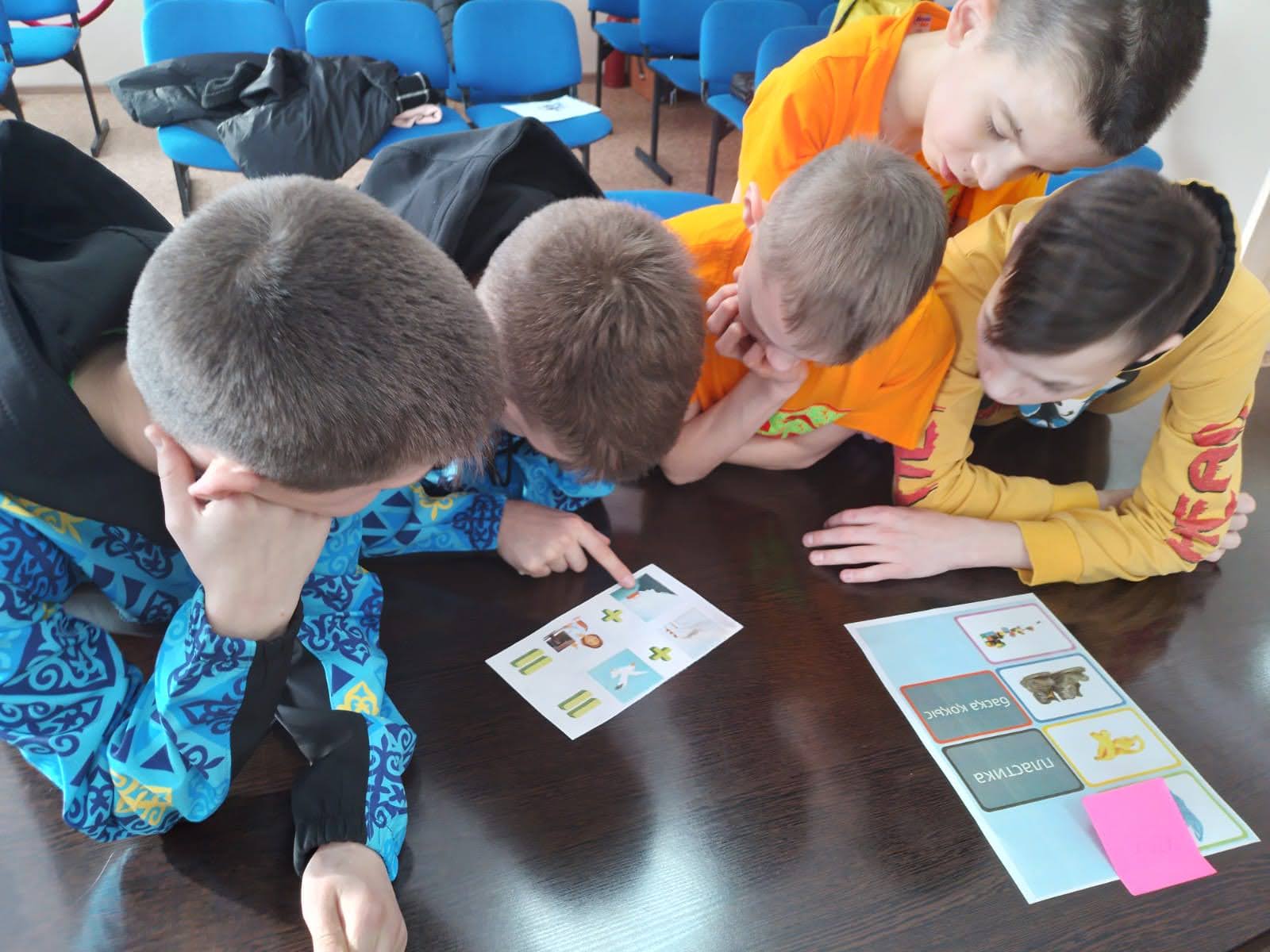 A group of students hover over a printed document sitting on a table.