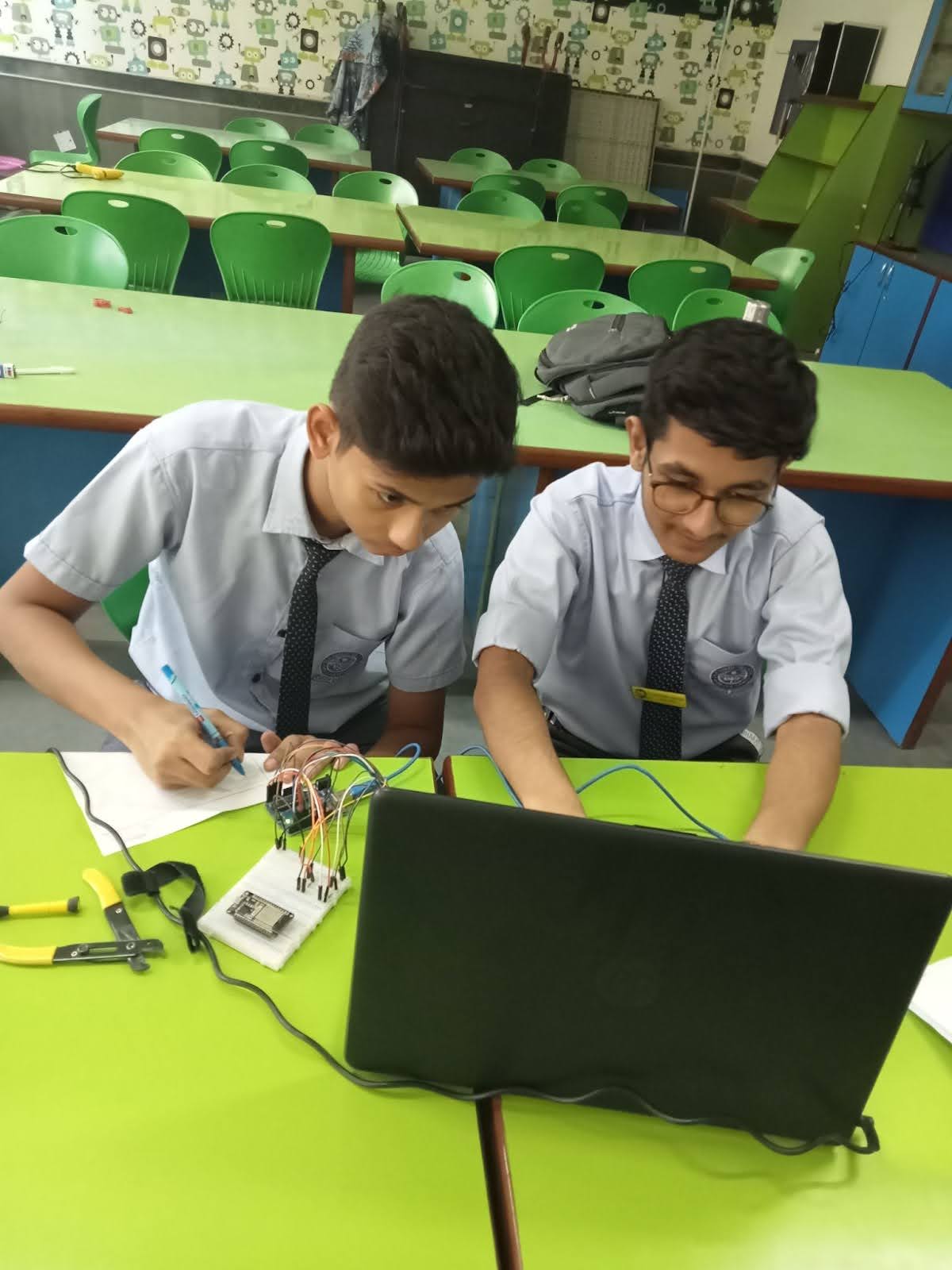 Two students work on a laptop and with their circuit boards