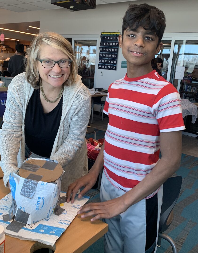 Teacher and student work at a desk with recycled materials. 