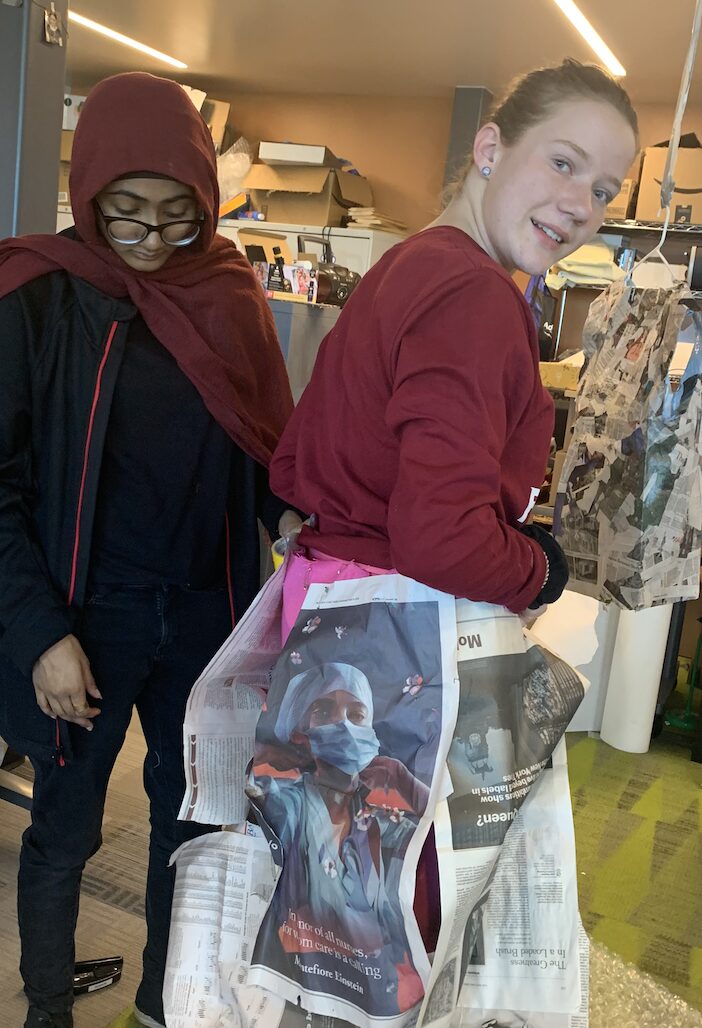 Two students work with a garment in the eco-justice fashion show.
