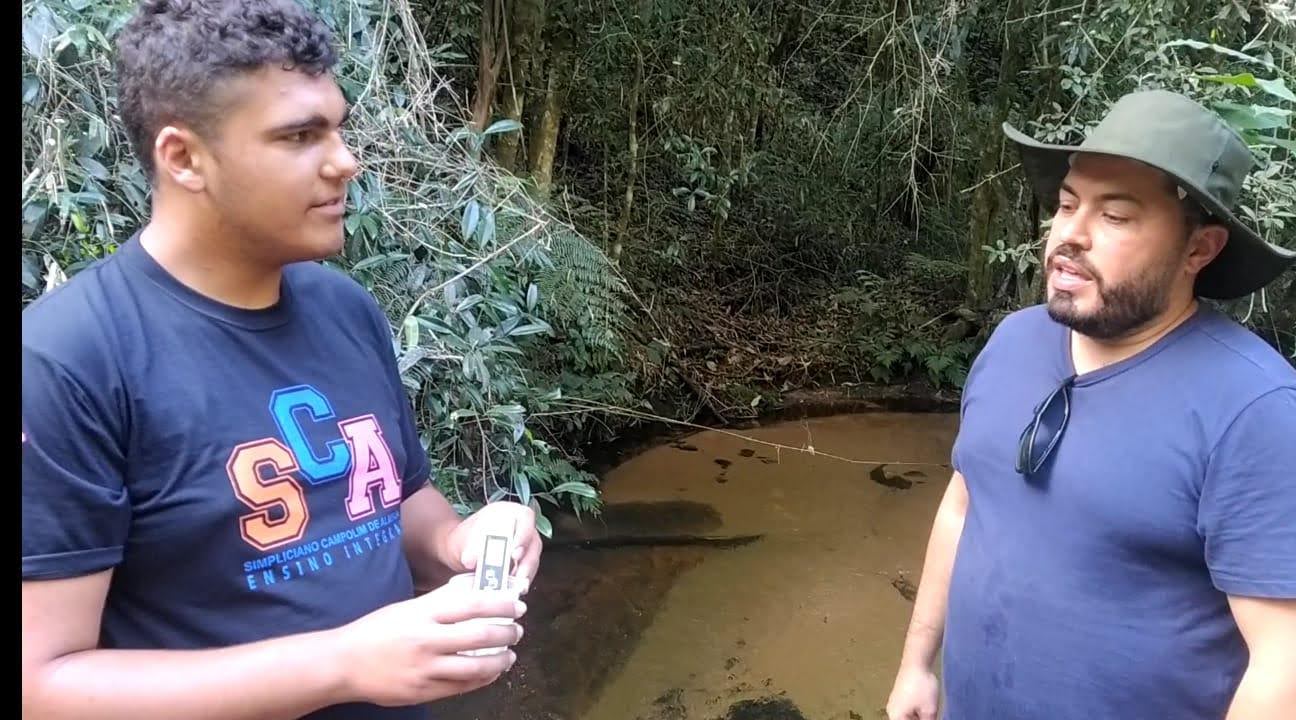 Two people have a conversation in a forest. 