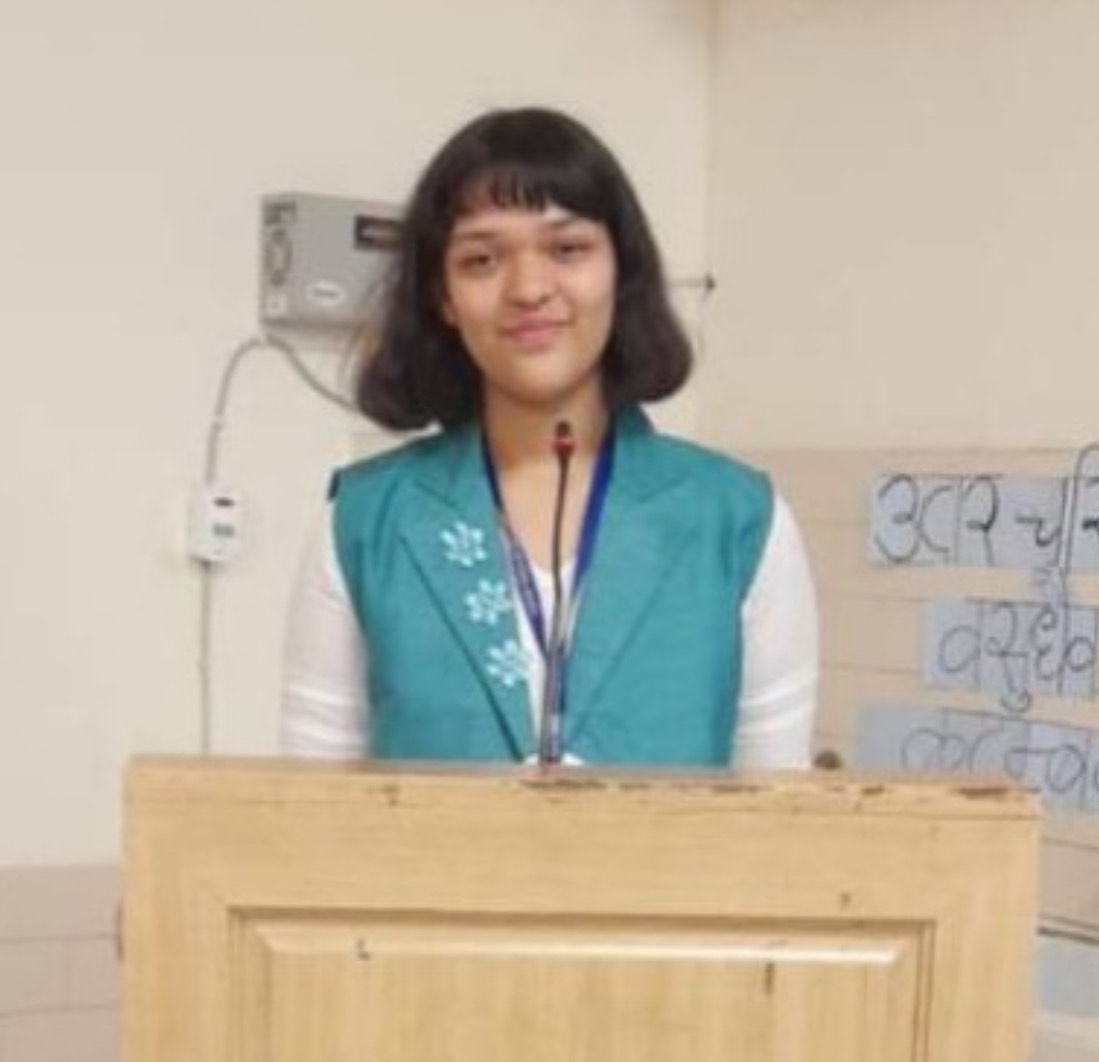 A student stands behind a podium with a microphone. 
