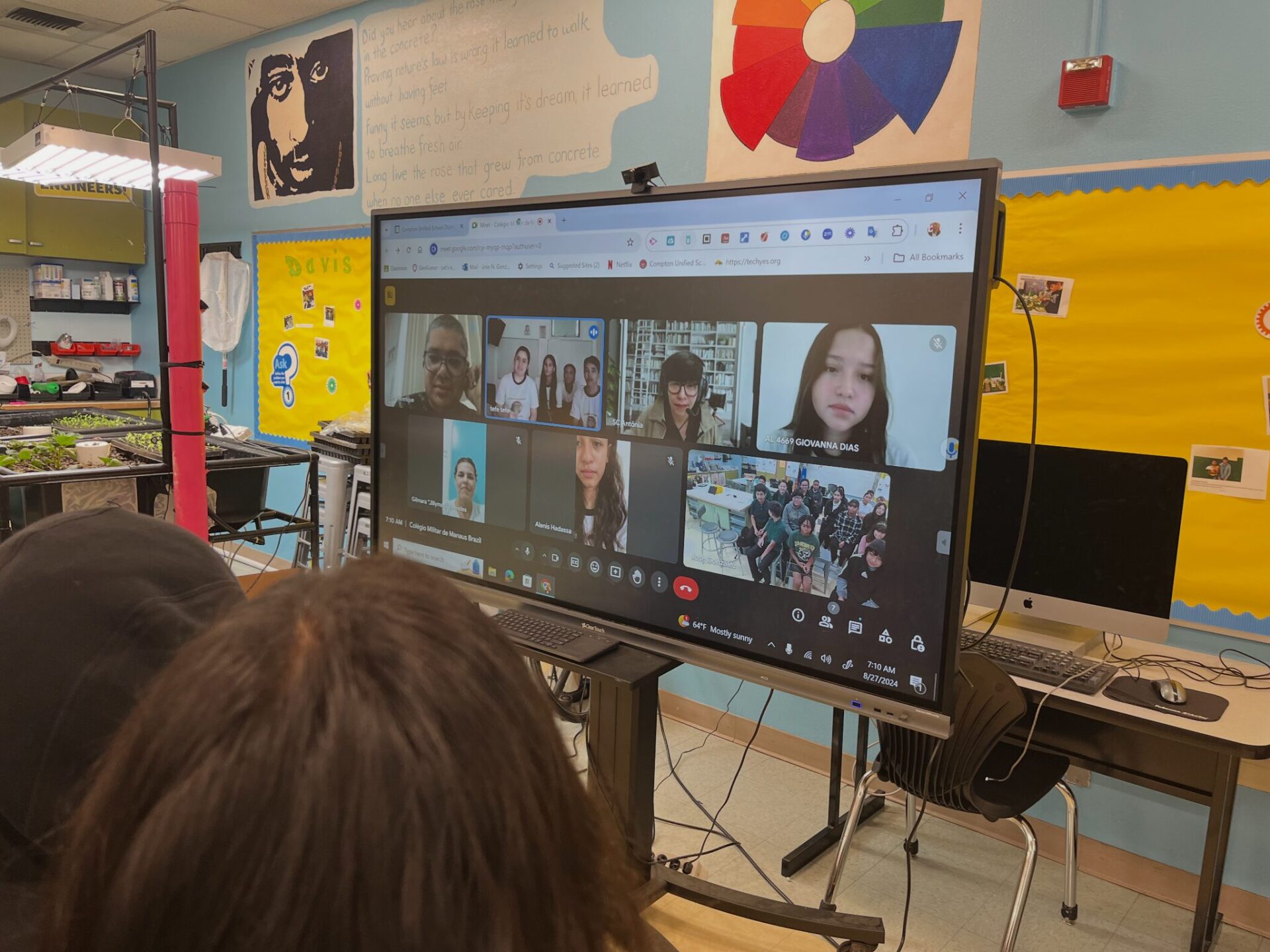 Students watch a TV displaying a Zoom meeting with their peers in Brazil